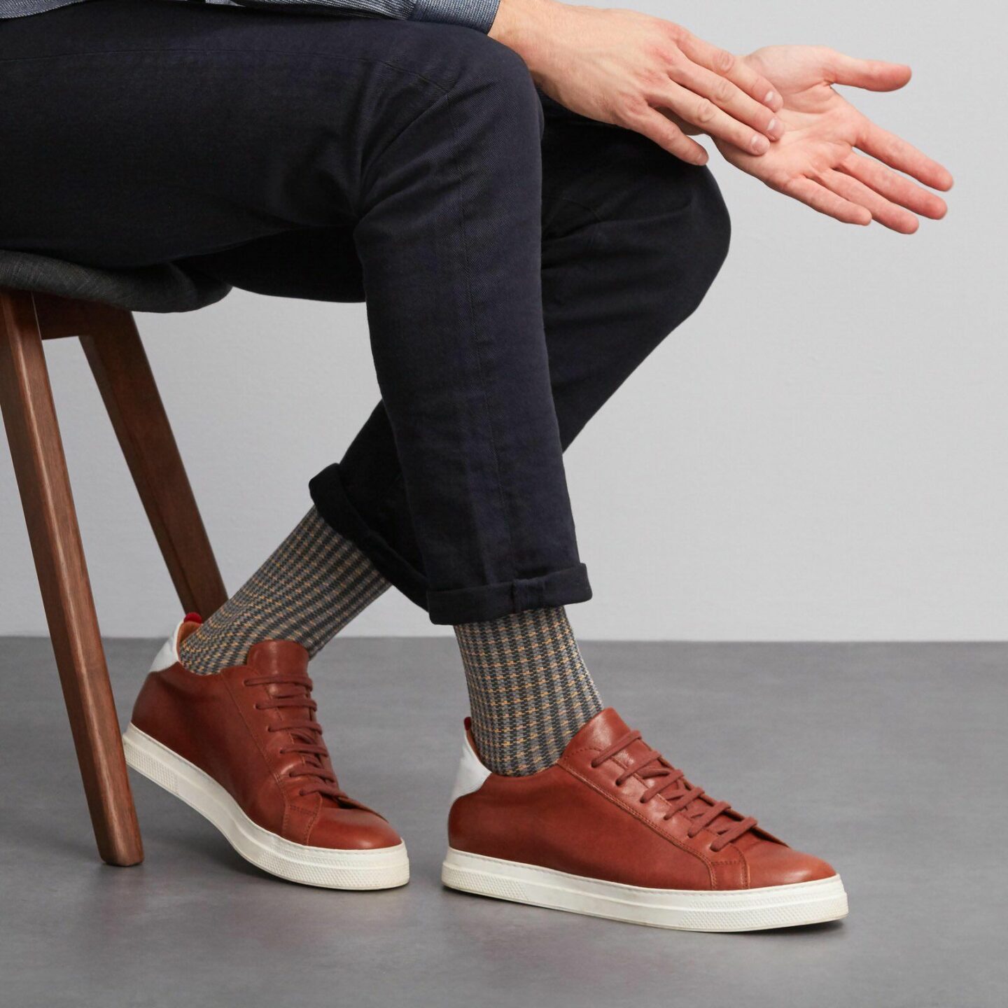 A close up of a person wearing patterned socks with brown shoes