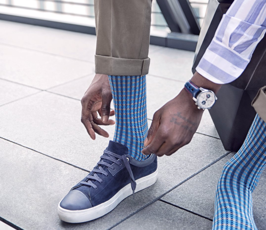 Black model wearing blue LSC socks and tying blue trainers