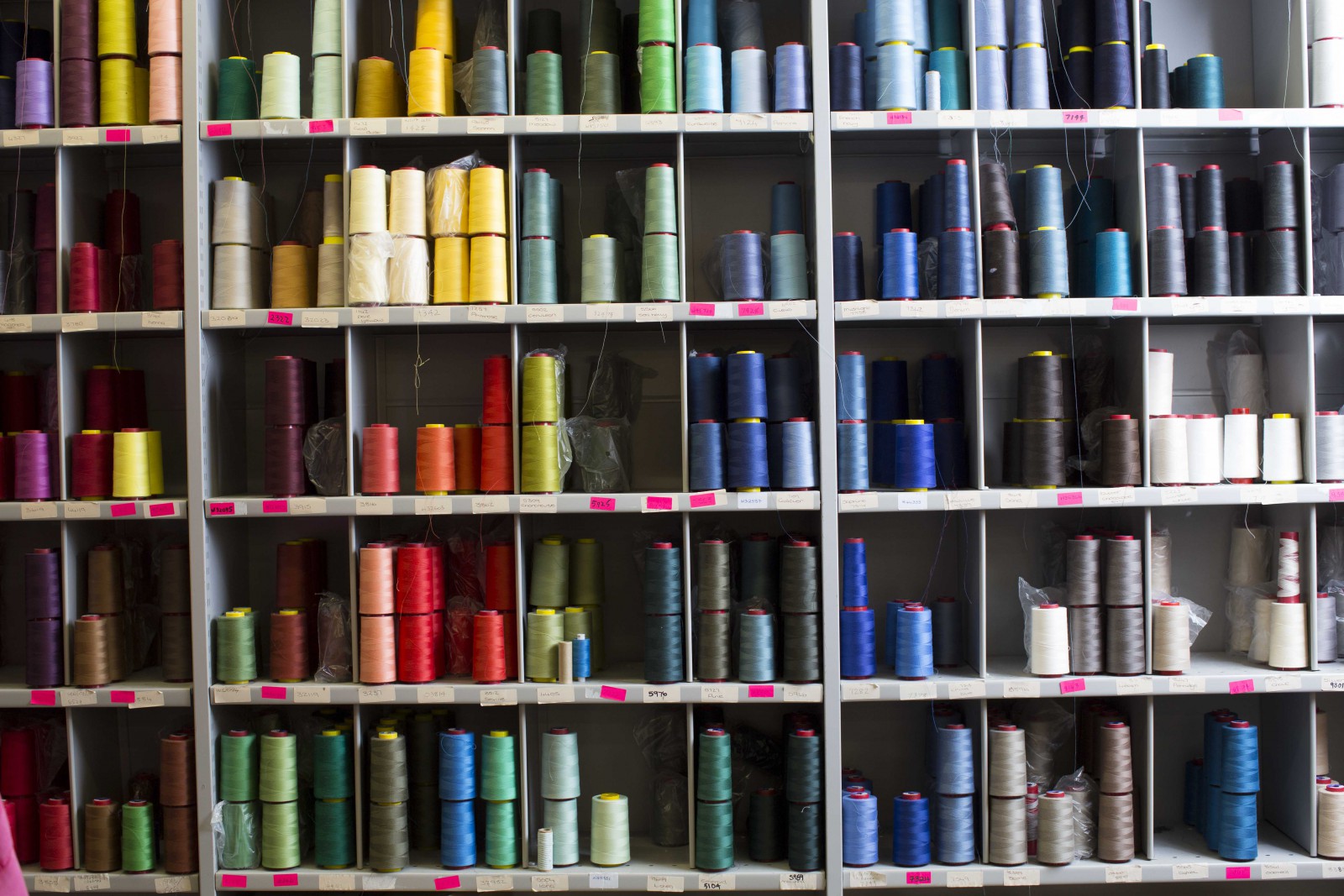 A wall of spools and yarn in a factory 